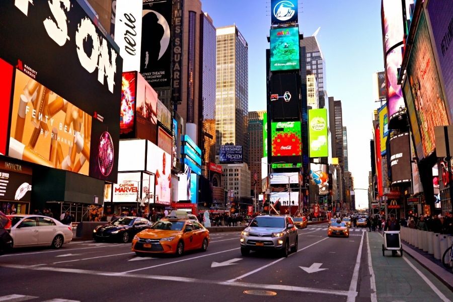 Crowds on Seventh Avenue in Times Square outside a large restaurant space